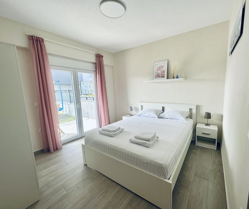 Bedroom 1 with a king-size bed and a glass door to the garden at Lora Family Apartment, Nikiti