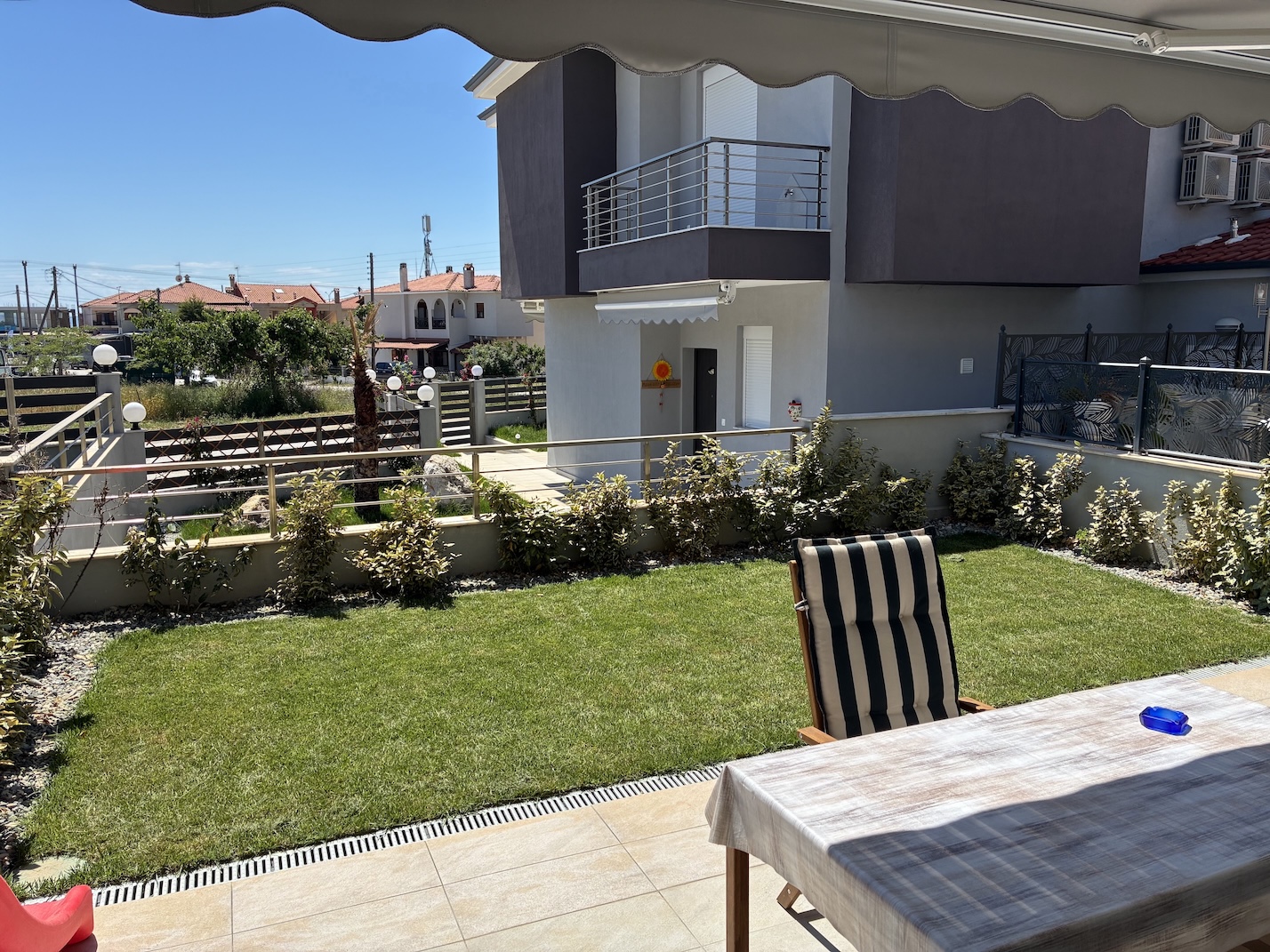Private garden with lawn and outdoor table, seen from the patio of Lora Family Apartment in Nikiti