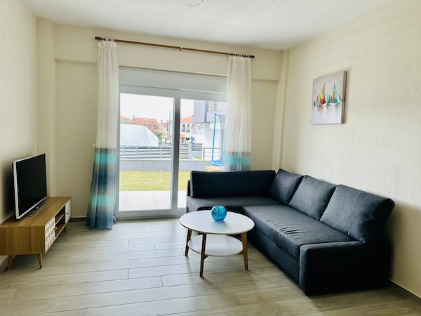 Living room with sofa, TV and glass door to the garden at Lora Family Apartment